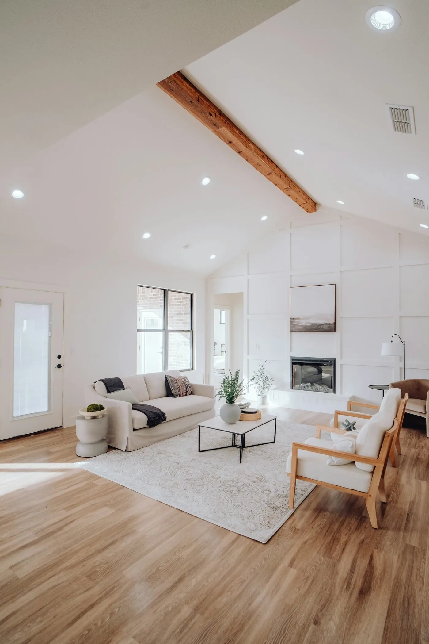 A bright vaulted living room with a timber beam and warm wood floors
